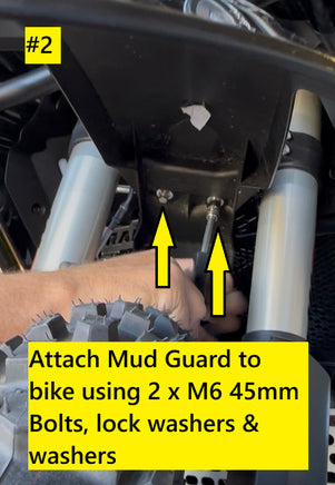 Close-up instructional photo showing a hand attaching a black spacer kit mud guard to a bike using two M6 45mm bolts, with yellow arrows and text overlays indicating the steps.