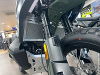 Close-up of a motorcycle's front wheel and suspension system in a showroom showing off a Polished Rad Guard for a CFMoto 1000 MT-X