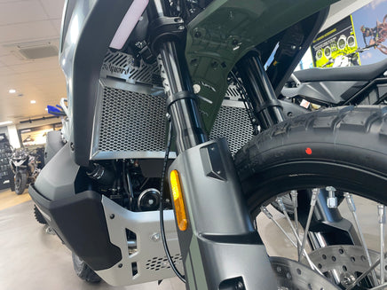 Close-up of a motorcycle's front wheel and suspension system in a showroom showing off a Polished Rad Guard for a CFMoto 1000 MT-X