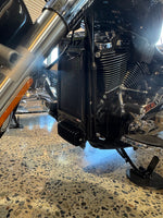 Close-up of a motorcycle engine on a textured surface for a Harley Davidson Heritage Classic 117 with a black rad guard