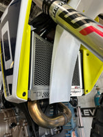 Close-up of a motorcycle's exhaust and engine components with visible branding, with the Rad Guard radiator guard in polished fitted. Perfect fit for a Husqvarna 701 Enduro or Supermoto.