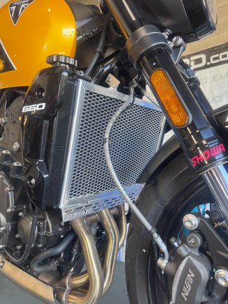 Close-up of a motorcycle radiator with 660' branding on a blurred background for a Triumph Trident 660 polished alloy radiator guard fitted 