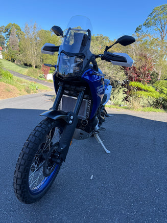 Blue motorcycle parked on a road with trees in the background showing a Polished aluminium radiator guard giving that much needed protection 