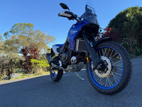 Blue motorcycle on a road with trees in the background, with a Rad Guard radiator guard fitted. Custom fit and model specific for ultimate protection and peace of mind
